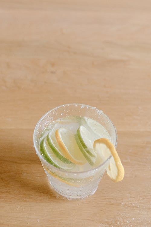 Glass with cocktail and lemon with lime slices on table