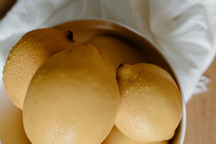 Bowl With Wet Lemons On Table Near Napkin