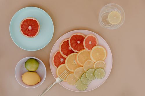 Free A vibrant top view of citrus slices, lemon, lime and grapefruit on plates with a fork. Stock Photo