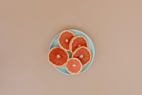 Free Top view of fresh sliced grapefruit on a ceramic plate with a plain background. Stock Photo
