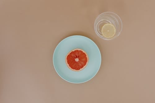 Plate with sliced red grapefruit near bowl with sliced lemon