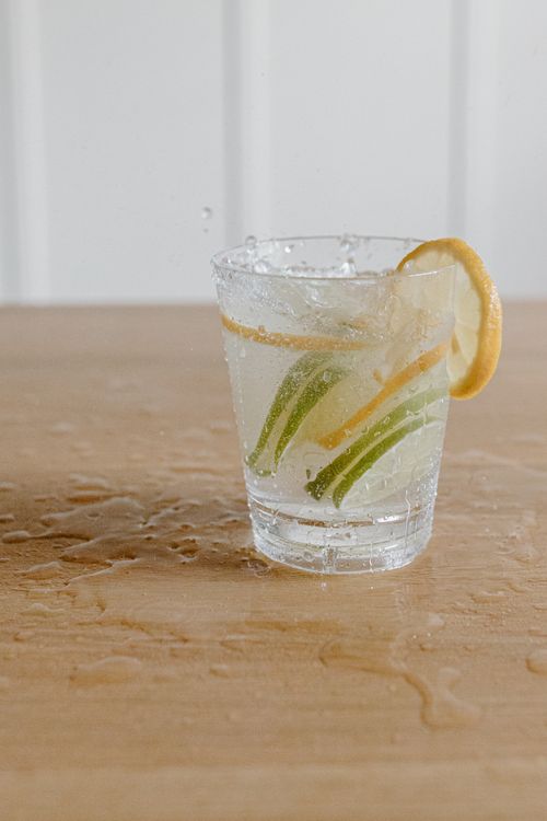 Free A refreshing drink with lemon and lime slices in a glass on a wooden table. Stock Photo