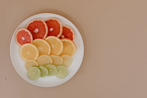 Plate with sliced lemons and oranges with grapefruits and limes
