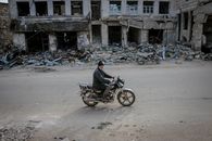 Man riding motorbike along destroyed building