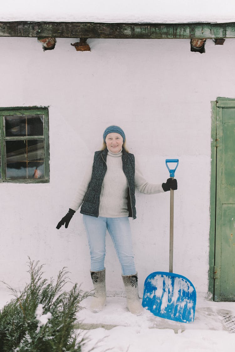 Woman In Wearing Winter Clothes Holding A Snow Shovel