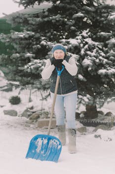 Elderly woman enjoying winter as she shovels snow, surrounded by a snowy landscape.