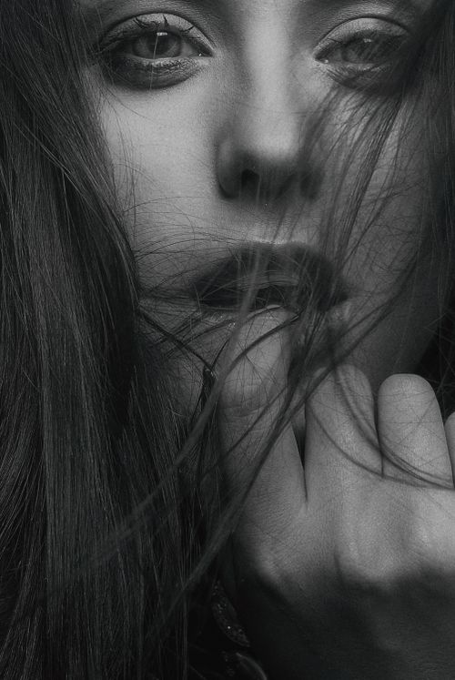 Free An artistic black and white portrait of a woman with her face partially covered by hair, conveying mystery. Stock Photo