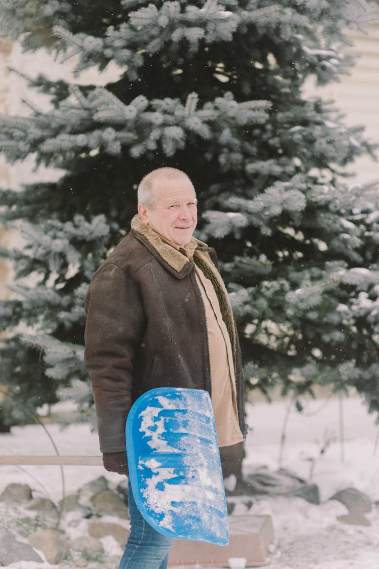 A Man Holding A Snow Shovel