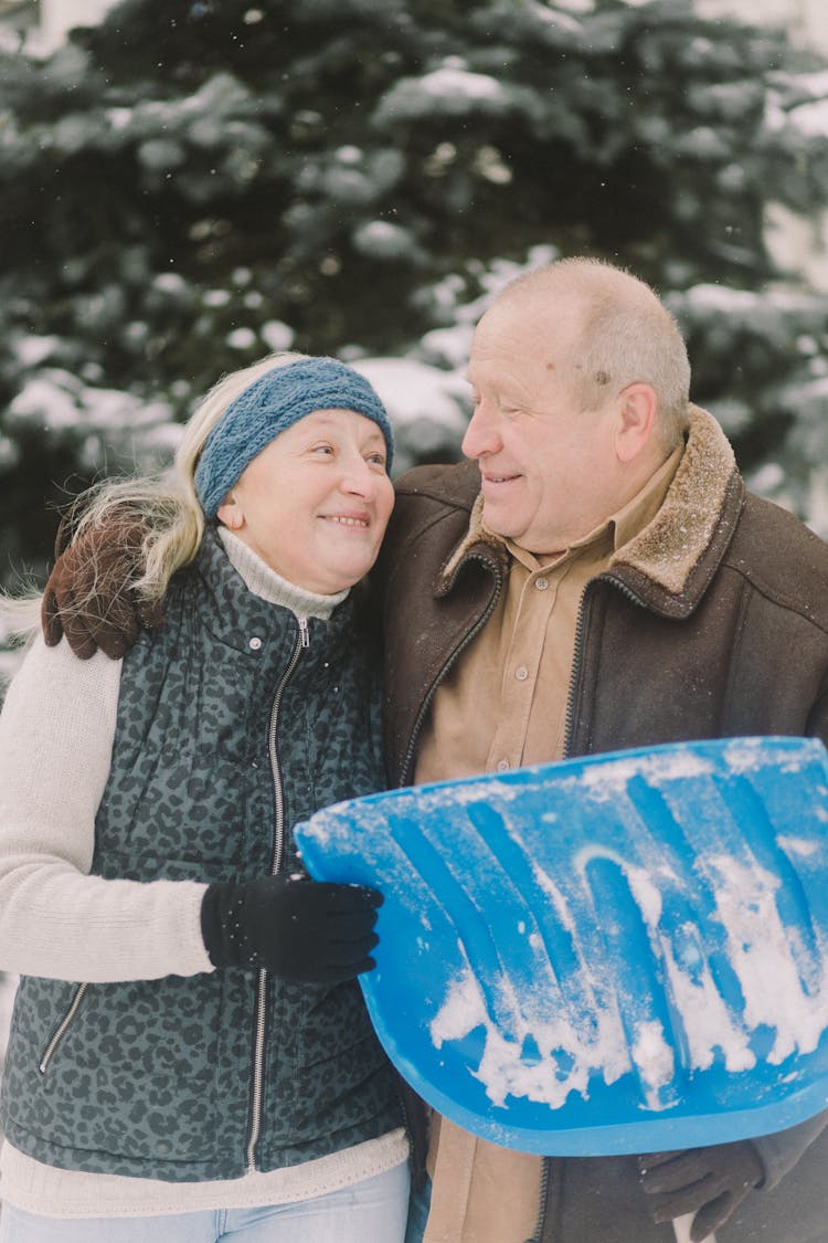 Portrait Of An Elderly Couple Holding Snow Shovel