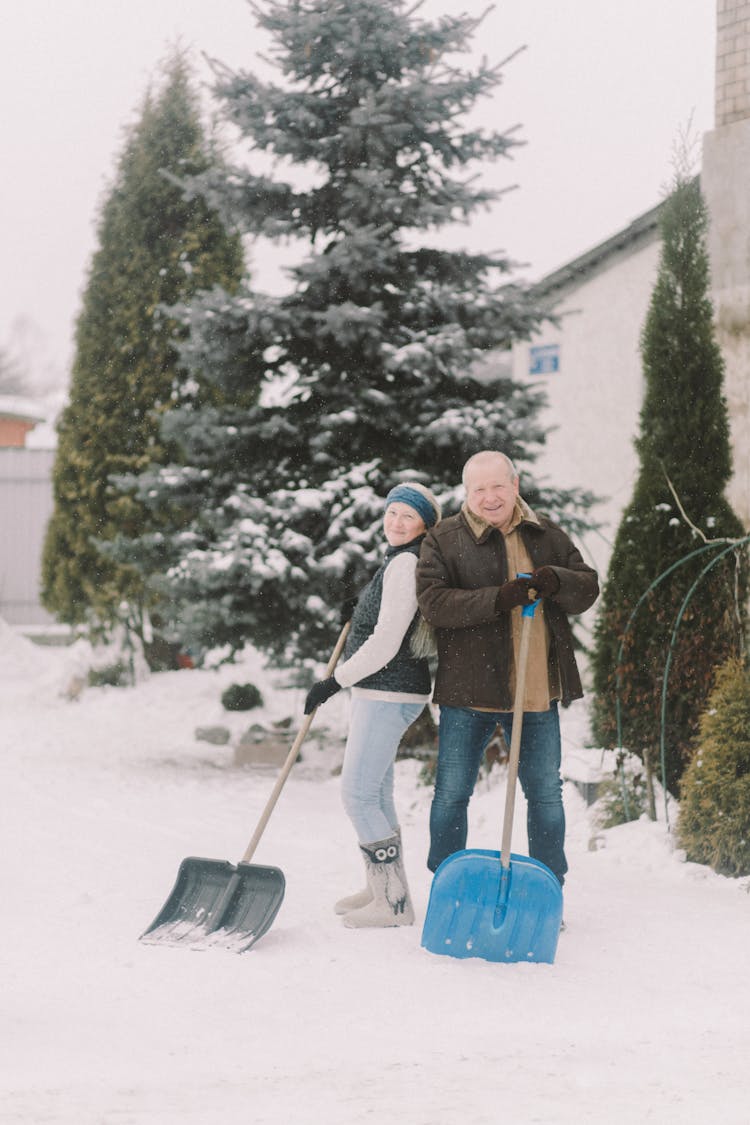 Elderly Couple Shoveling Snow Together
