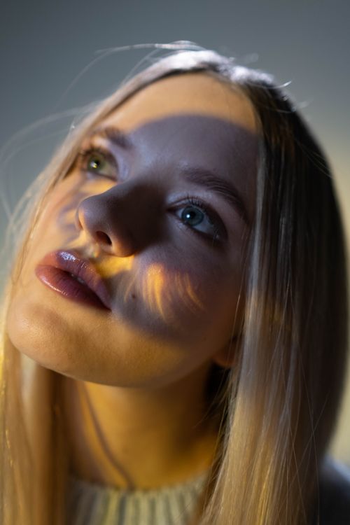 Free A dreamy close-up portrait of a woman looking up with artistic light effects and shadows. Stock Photo