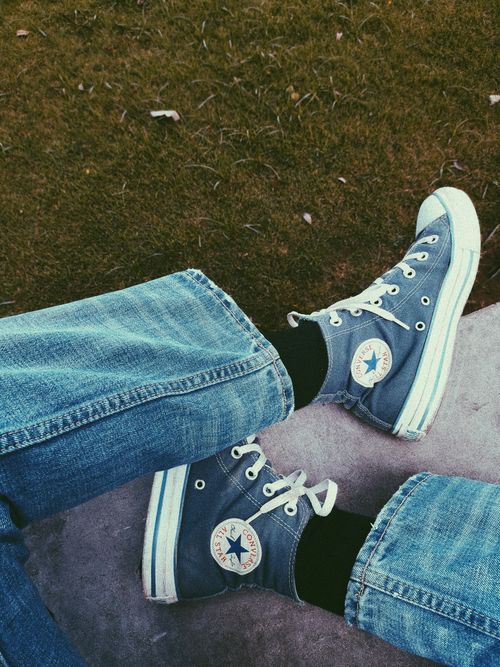 Free Person wearing denim jeans and Converse sneakers relaxing outdoors. Stock Photo