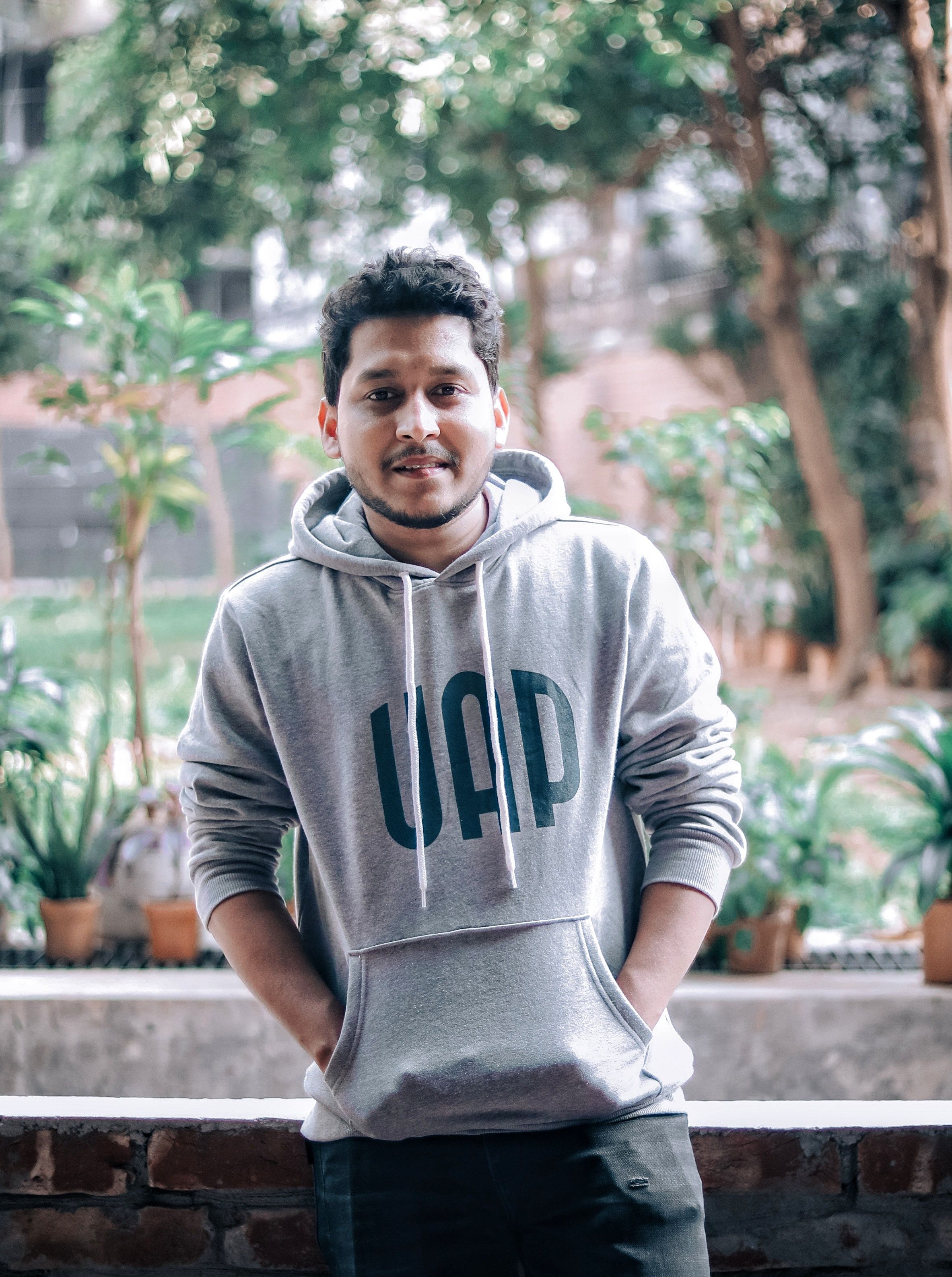 Young man wearing a hoodie outdoors, hands in pockets, casual vibe.