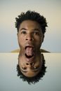 Man's Head with Tongue Out Resting on Mirror