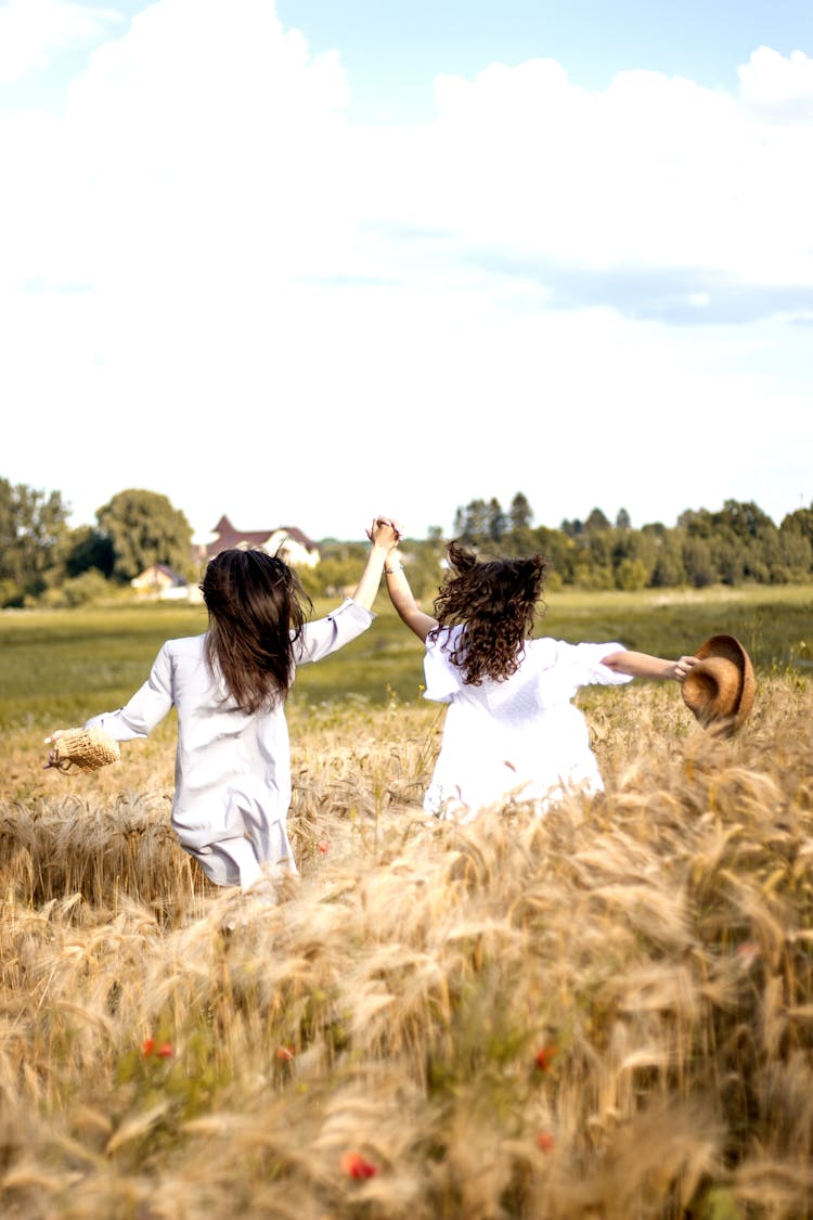 Two Children Holding Hands Hopping In A Field