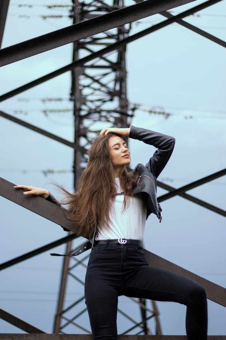 Woman Wearing Black Jacket And Pants Posing On Lattice Tower