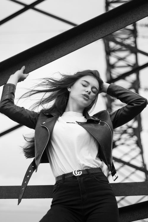 Free Artistic black and white photo of a woman posing against an industrial background. Stock Photo