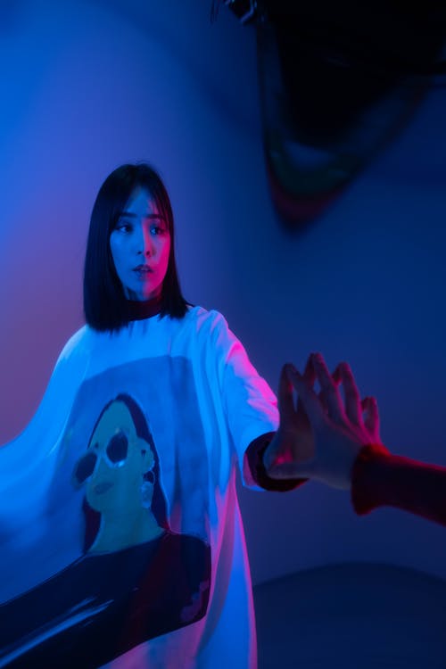 A Woman in a White Shirt Touching a Mirror