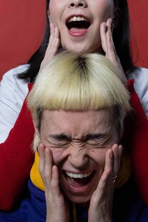 Free Two young Asian models express surprise and fun in a colorful indoor setting. Stock Photo