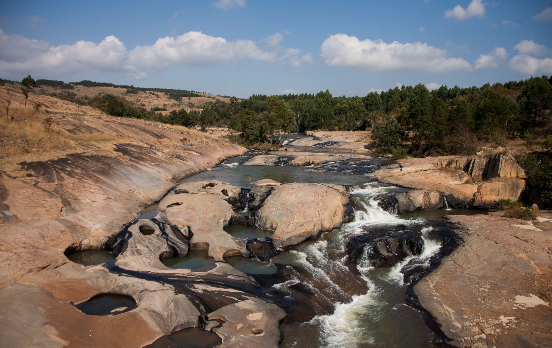 Stunning view of rocky cascades and trees along a river in Eswatini, showcasing natural beauty and tranquility.