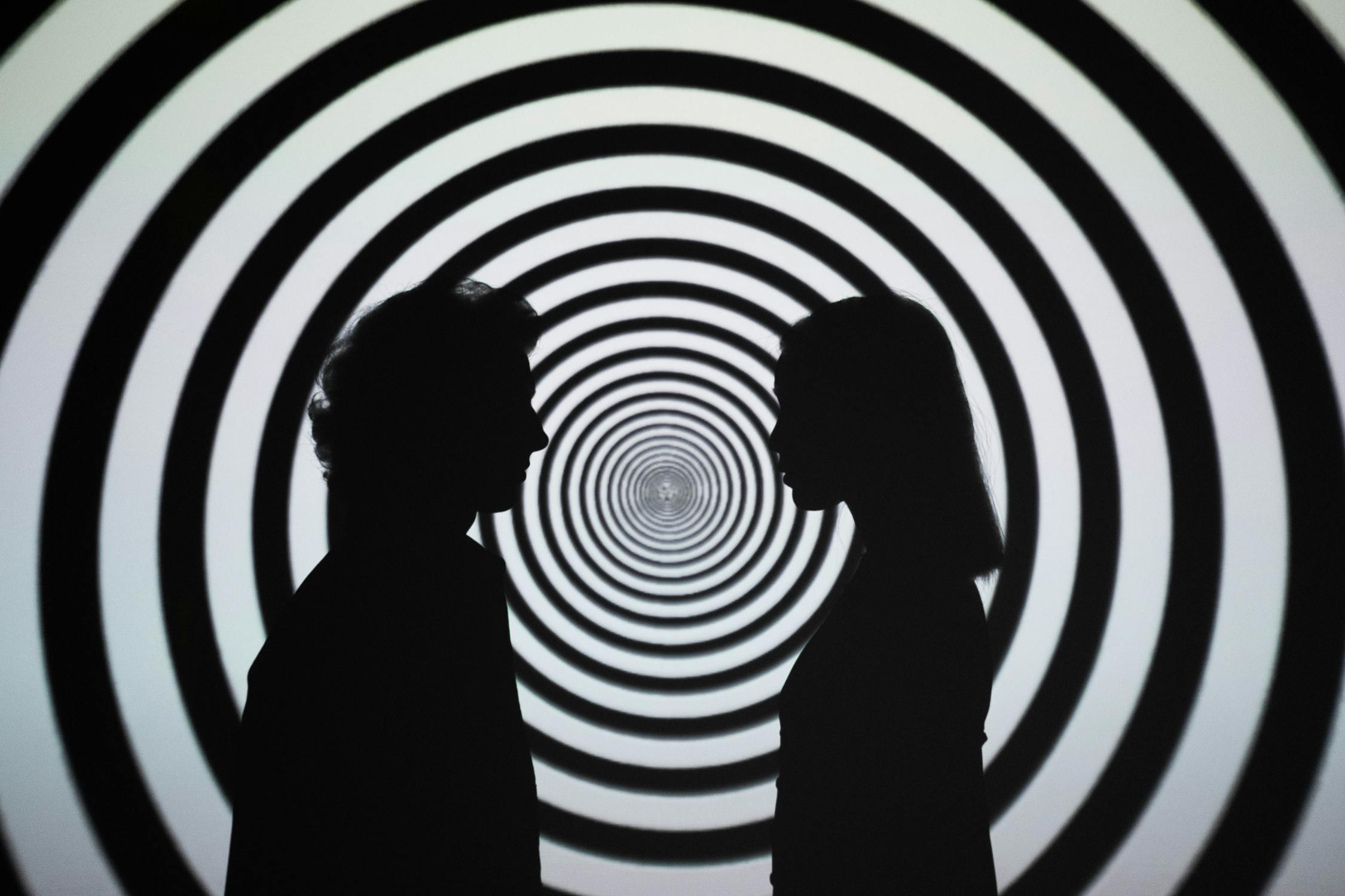Silhouette of 2 Person Standing in Front of White and Black Stripe Wall