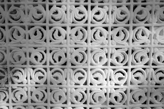 Detailed white metal lattice pattern with intricate designs seen outdoors.