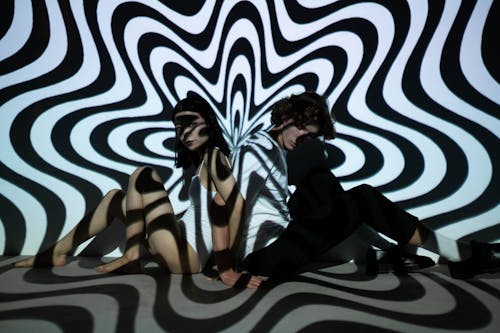 Two People Sitting Near Black and White Wall