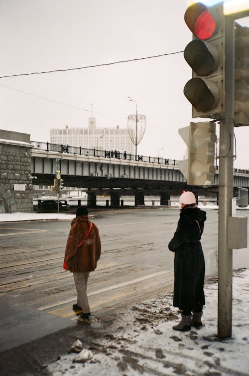 Anonymous women walking on zebra crossing on cloudy winter day