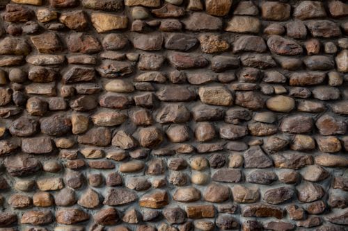 Free Textured rustic stone wall displaying a variety of natural stones in earthy tones. Stock Photo