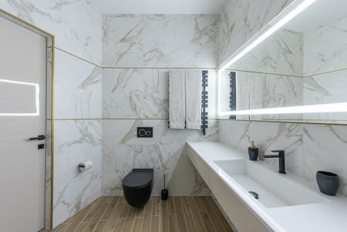 Interior of contemporary bathroom with marble walls and ceramic sink in modern minimalist apartment