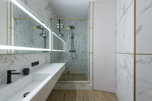 Elegant contemporary bathroom featuring marble tiles, walk-in shower, and illuminated mirror.