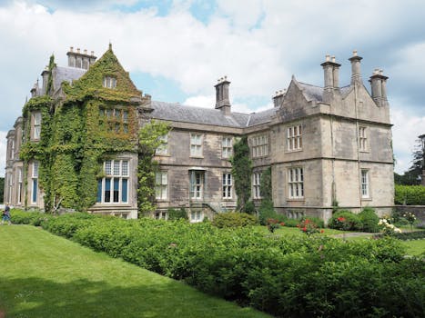 Beautiful stone mansion with ivy-covered walls and lush garden, exuding historic charm.
