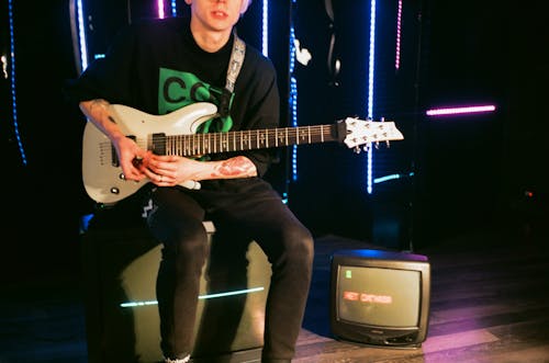 Crop guitarist with bass guitar sitting in studio