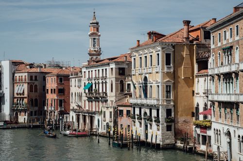 Free Exterior of old residential houses and tower located along famous Grand canal with gondolas in water of Venice Italy Stock Photo