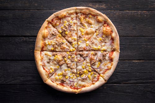 Tasty pizza with canned corn grains on wooden surface