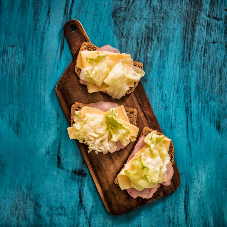 Delicious Sandwiches With Cheese And Ham Slices On Cutting Board