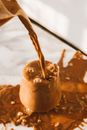 Pitcher Pouring Brown Liquid in an Overflowing Clear Glass