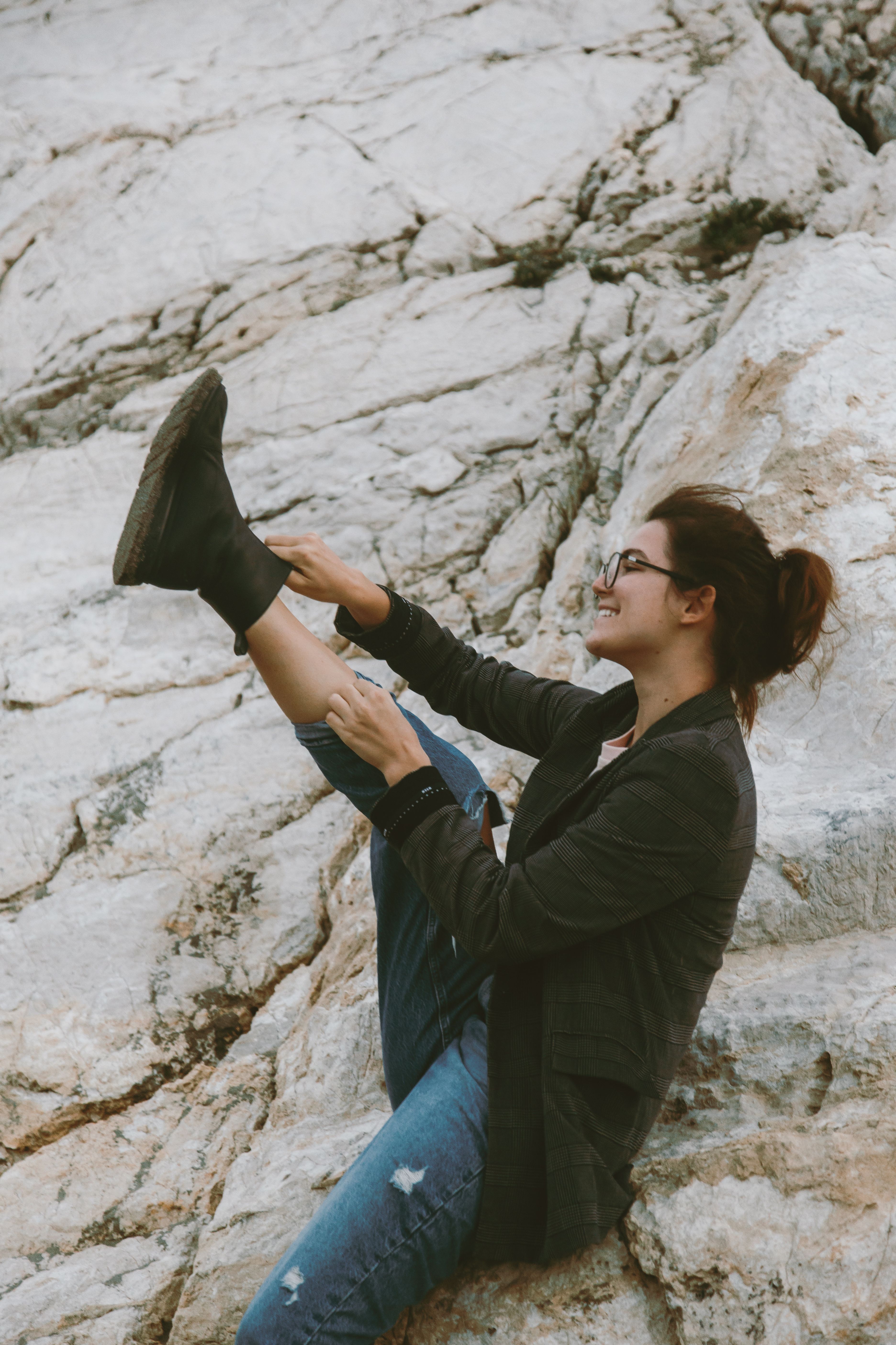 Smiling woman in black jacket on rocks, showcasing joy and adventure.