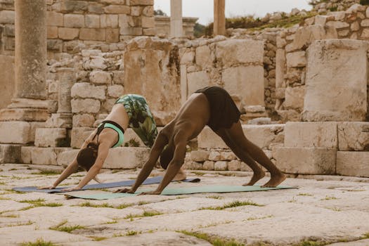 Two people practicing yoga in ancient ruins, emphasizing health and wellness outdoors.