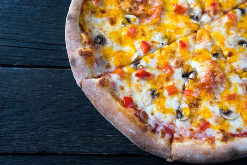 Free From above of appetizing pizza with mushroom and red pepper pieces on melted cheese on dark background Stock Photo