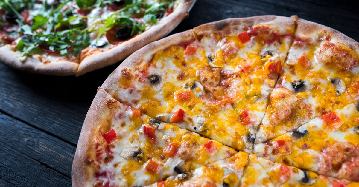 Mehrere Pizzen mit Gemüse und Pilzen auf geschmolzenem Käse vor dunklem Hintergrund
