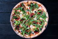 Tasty pizza with arugula leaves on dark background