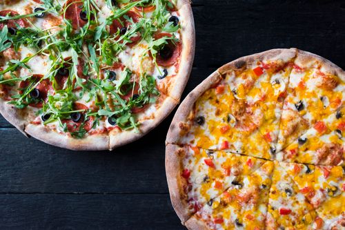 Free Overhead view of delicious pizzas with mushroom and pepperoni pieces under fresh herb leaves on dark background Stock Photo