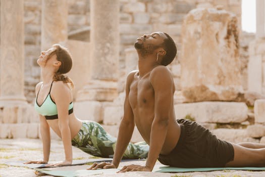 A man and woman practice yoga poses on mats outdoors, embracing a healthy lifestyle.