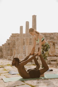 Yoga session with a man and woman practicing poses among ancient ruins outdoors.