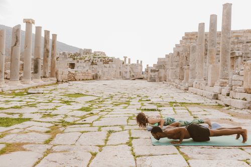 Free Two individuals workout on mats among ancient columns, blending fitness with history. Stock Photo