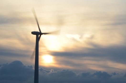 A wind turbine spins amidst a vibrant sunset sky, symbolizing renewable energy.
