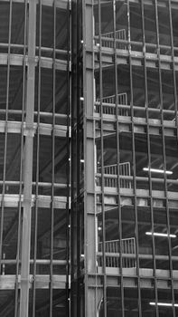 Black and white image of a modern building facade with visible staircases, showcasing steel and glass architecture in Amsterdam.