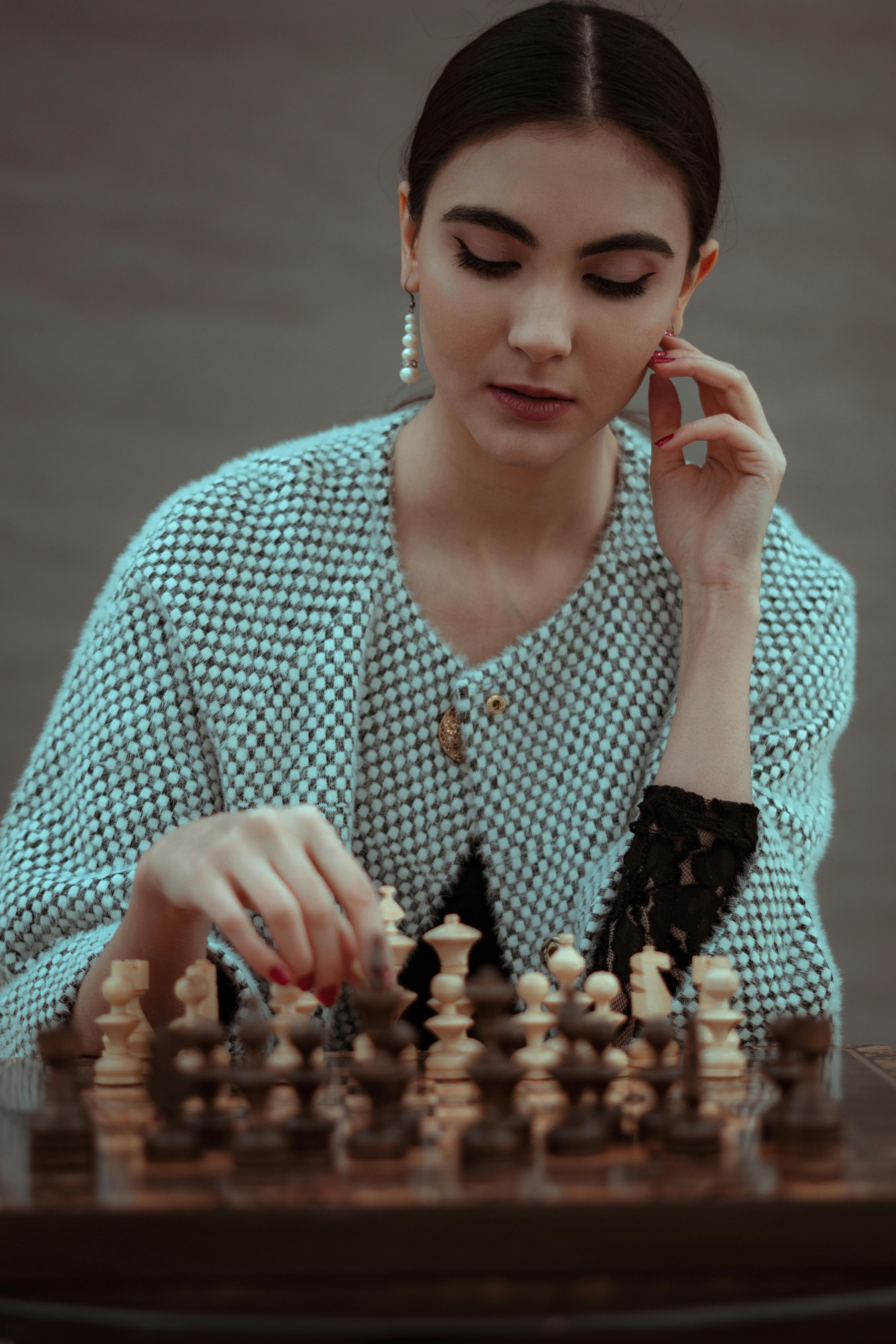 Young woman deep in thought while playing chess indoors, focusing on strategy and intellect.