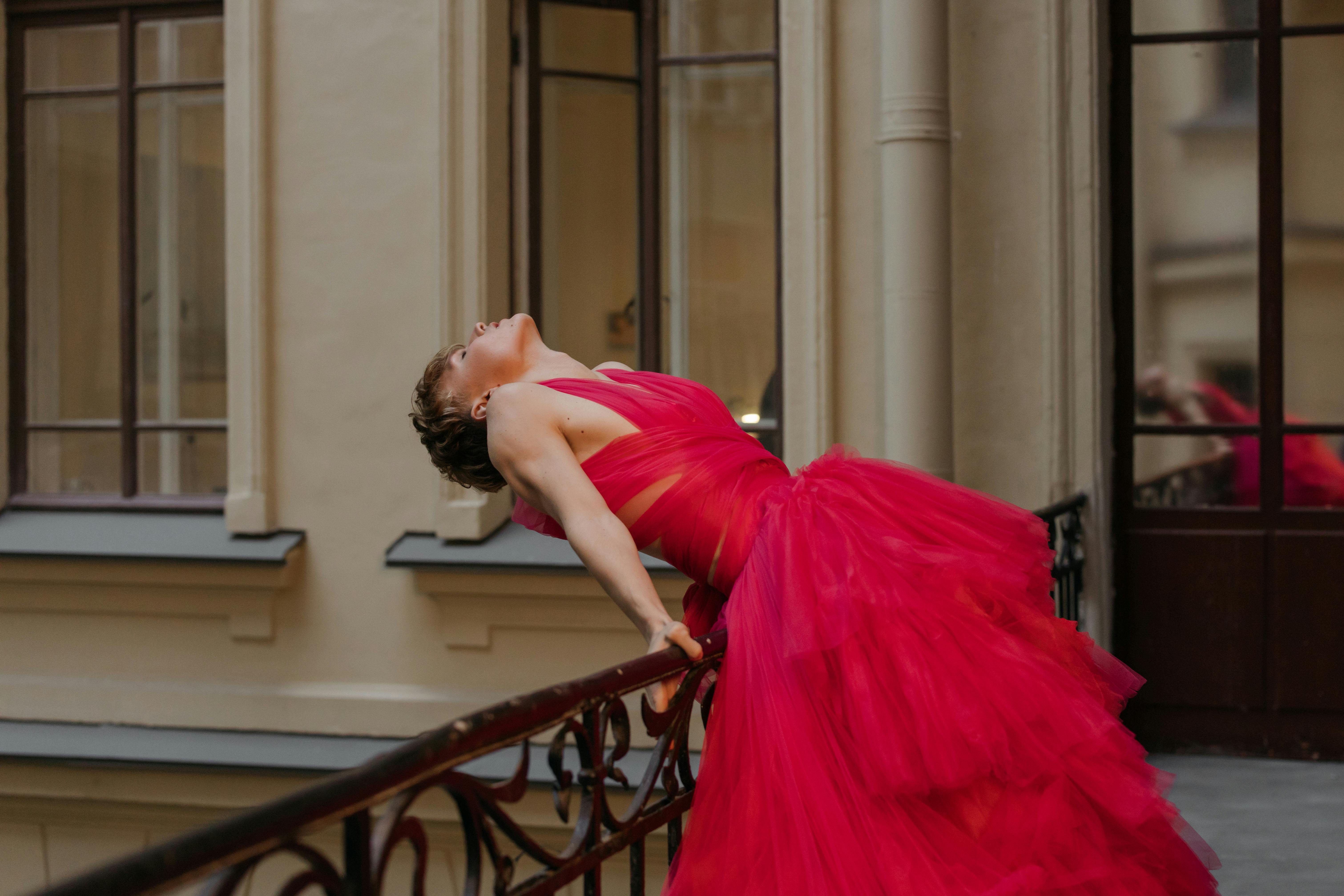A Woman in Red Dress Leaning Back on a Railing · Free Stock Photo